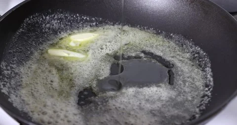 Adding olive oil to butter to prevent it from burning Stock Footage 217508414