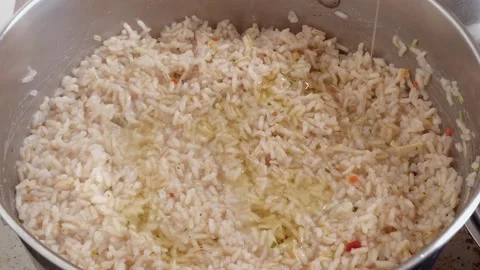 Adding olive oil to cooked rice in a pot for flavor and texture enhancement Stock Footage 341934933