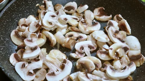 Adding olive oil to mushrooms that are frying in a hot pan. Slow motion100fps. Video stock 309300049