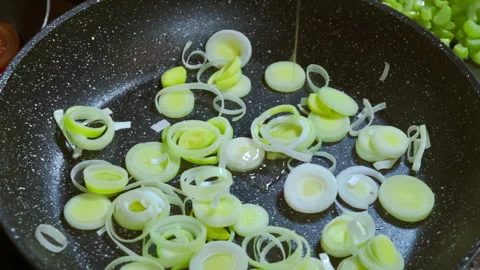 Adding olive oil to sliced leeks that are frying in a pan. Stock Footage 315272440