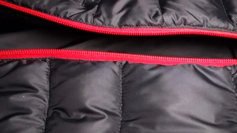 Adding one half of the red zipper to the other on a black winter windbreaker Stock Footage 169893838