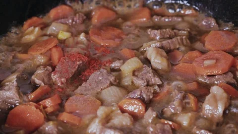 Adding paprika to beef stew with vegetables close-up Stock Footage 102777354