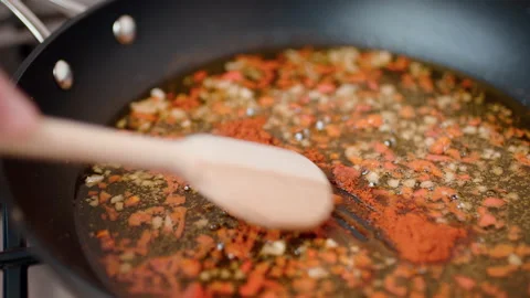 Adding paprika powder into a frying pan with chili and oil on a gas stove in 4K. Stock Footage 138408341