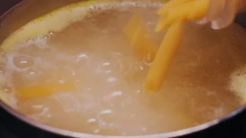 Adding penne pasta to boiling water. Close-up of pasta cooking. Stock-Footage 335807082