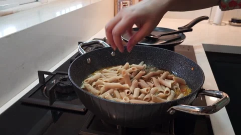 Adding Penne Pasta to Homemade Curry Sauce for Cooking Stock Footage 345164220