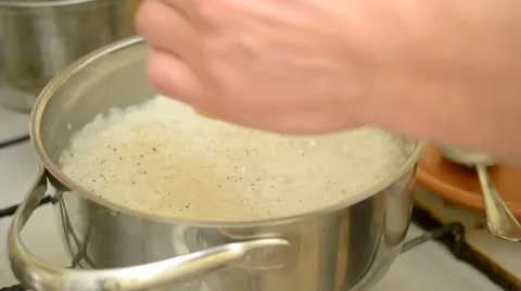 Adding pepper and salt to rice boiling in saucepan Stock Footage 46339346