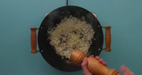 Adding pepper to onions cooking in a skillet 스톡 동영상 132198643
