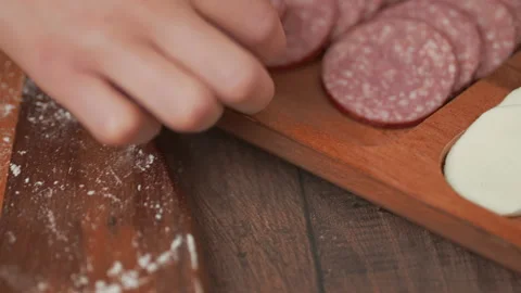 Adding pepperoni on top of a pizza dough. Concept of preparation in 4K. Stock Footage 137430535
