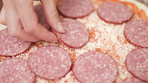 Adding pepperoni on top of a pizza dough. Concept of preparation in 4K. Stock Footage 137430782