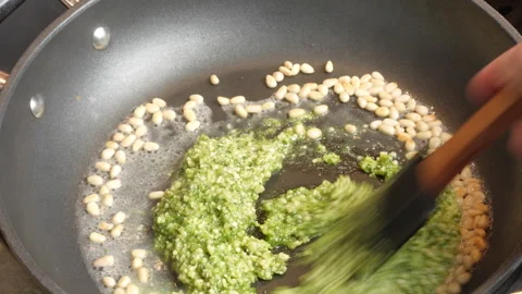 Adding pesto to pine nuts in a pan to make pesta pasta. Video stock 302021039