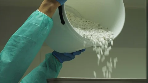 Adding  pills from bucket to the drug prodution machine in factory by worker. Stock Footage 106807515