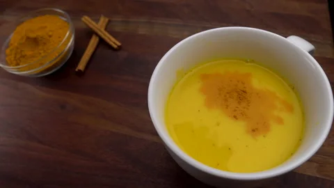 Adding Pinch of Turmeric Spice Powder to Healthy Golden Milk Latte 스톡 동영상 144576297