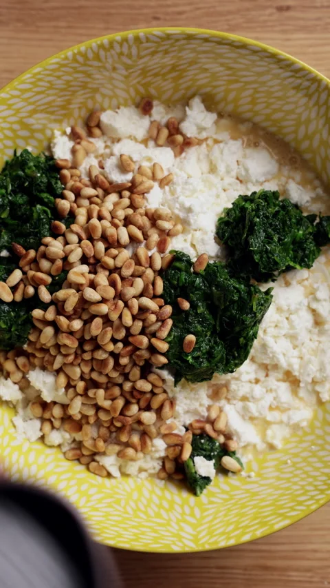 Adding Pine Nuts To Spinach Feta Bowl Top View Vertical Stock Footage 337247604
