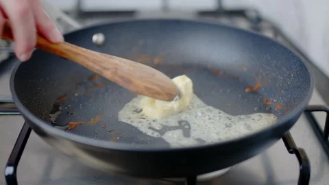 Adding, placing heavy cream into a preheated pan, melting into a liquid in 4K. Stock Footage 138066941