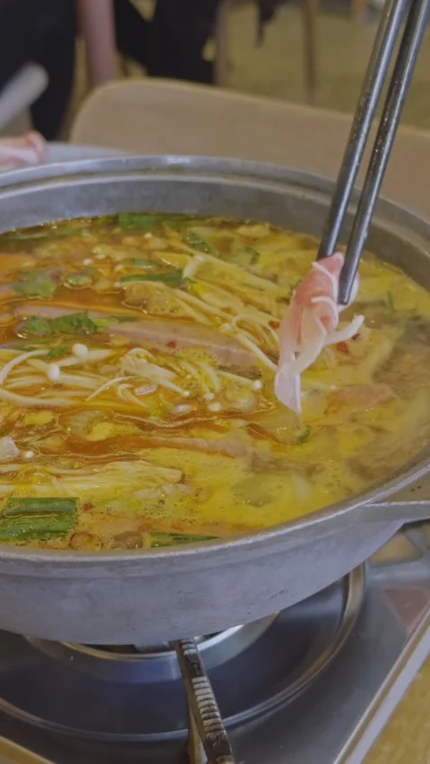 Adding pork slices to spicy tomato hot pot Stock Footage 314985065