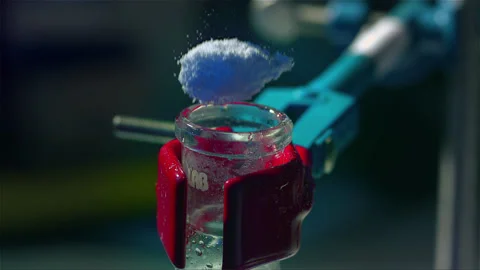 Adding a powder substance to a chemical experiment Stock Footage 257033193