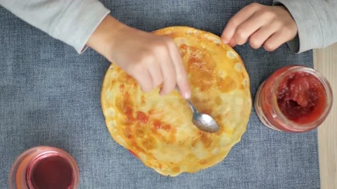 Adding putting Roseberry jam on french crepes in a serving plate. Concept of Stock Footage 228714072