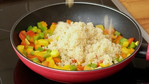 Adding quinoa to the pan with vegetables. Gluten free food. Stock Footage 254240630