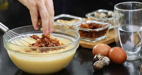 Adding raisins to the liquid dough with further mixing in a transparent bowl Stock Footage 151738041