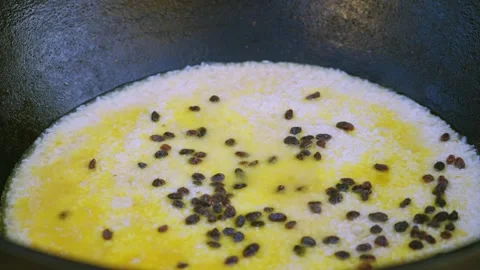 Adding raisins to pilaf in a large cauldron close-up Stock Footage 333040193