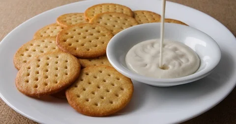 Adding ranch dressing to a bowl with crackers on a white plate Stock Footage 89804132