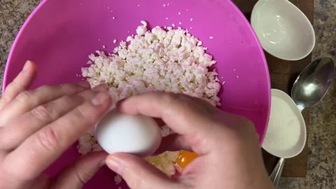 Adding raw chicken eggs to the cottage cheese in a bowl  動画素材 301325093