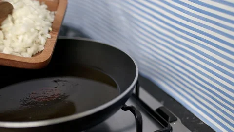 Adding raw chopped onion into a frying pan. Stock Footage 134689329