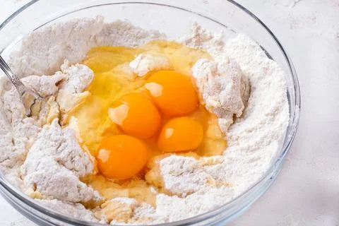 Adding raw eggs to yeast dough Stock Photos