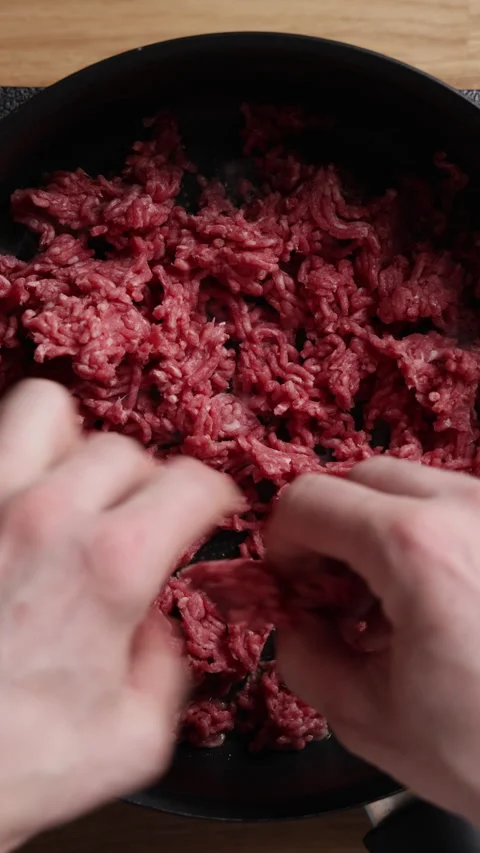 Adding Raw Ground Beef to Frying Pan Vertical Top View Видео 336569477