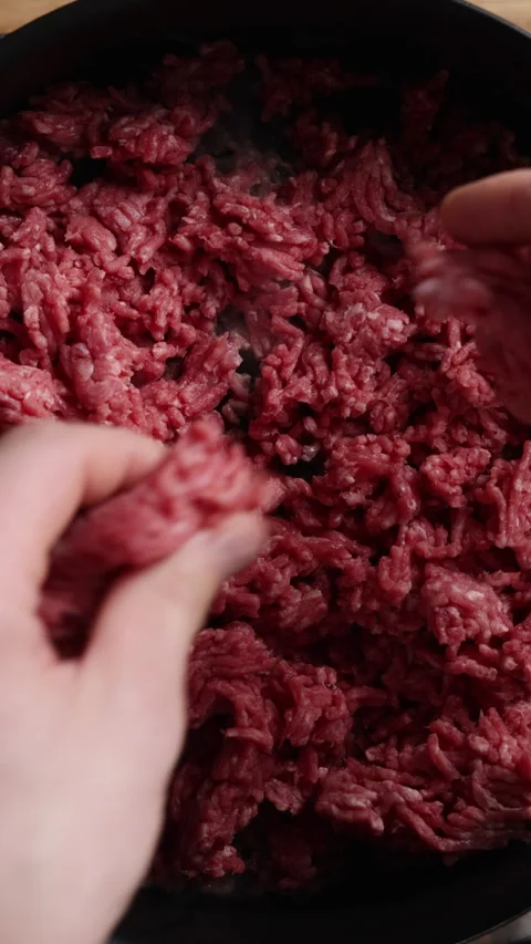 Adding Raw Ground Beef to Frying Pan Vertical Top View Close Up Видео 336570098