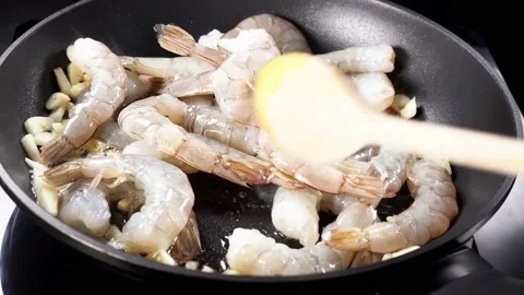 Adding raw prawns in a pan with garlic and hot olive oil Stock Footage 144081564