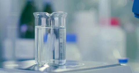 Adding a reagent to a glass beaker in a lab Stock Footage 76617590