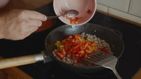 Adding red bell pepper to minced meat with yellow pepper in pan Stock Footage 315243735