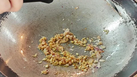 Adding red chili powder to sautéed garlic and shallots in a wok. 스톡 동영상 339182676