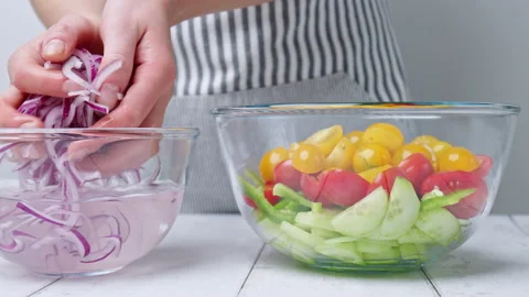 Adding red onion into a Greek Salad by removing them from vinegar water in 4K. Stock Footage 142115039