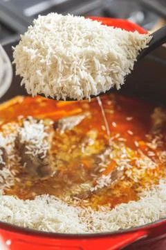 Adding rice to Pilaf being cooked at home Stock Photos