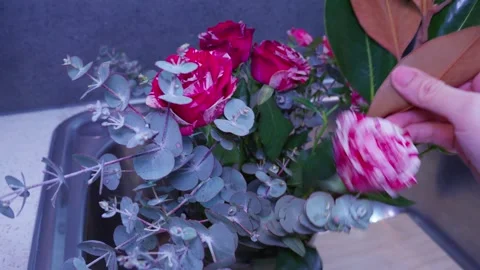 Adding Roses and Leaves to Vase for Home Floral Arrangement Stock Footage 319920277