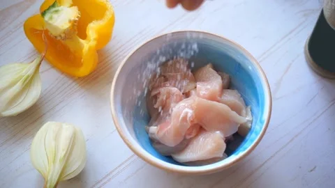 Adding salt and pepper into raw chicken bowl, home cooking Stock Footage 133052202