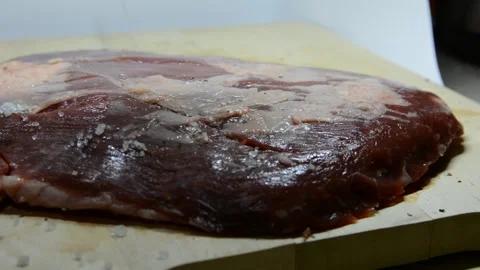 Adding salt and seasoning to beef.salt and pepper a peace of fresh meat Stock Footage 139980552