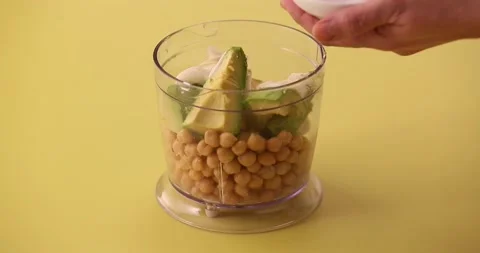 Adding salt to blender of chickpeas, avocados, lime, and tahini 2 Stock Footage 132207719