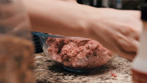 Adding salt into the ground beef and mixing it by hand afterwards Stock Footage 102570120