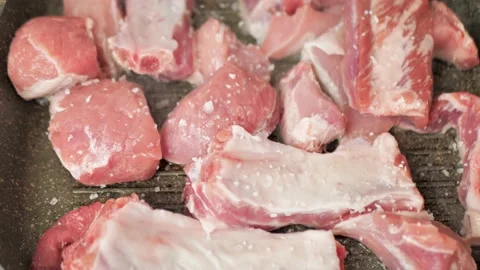Adding salt to pieces of meat that are fried on a grill pan Video stock 219418688