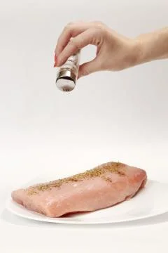 Adding salt on raw pork tenderloin with rosemary on top Stock Photos