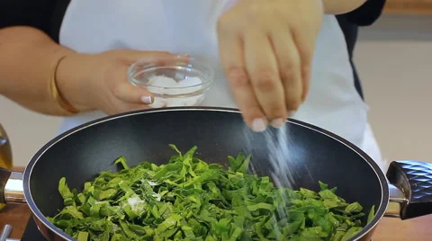 Adding salt into Spinach and rocket, salting Shish Barak with Yogurt Recipe Stock Footage 68772458