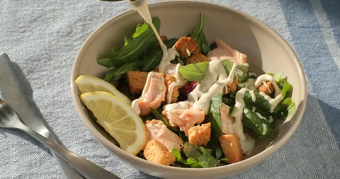 Adding sauce to Caesar salad with salmon Video stock 295066472