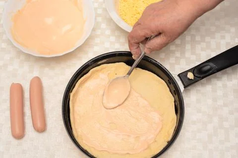 Adding sauce on the raw dough on black pan for homemade pizza by senior woman Stock Photos