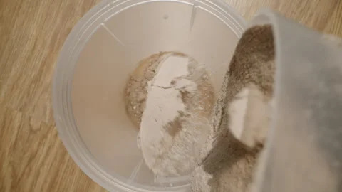 Adding a scoop of chocolate Protein Powder to the milk in the shaker, camera Stock Footage 283787030