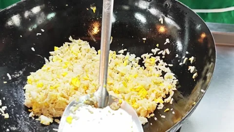 Adding seasoning ingredients to egg fried rice in a wok. Stock Footage 342394027