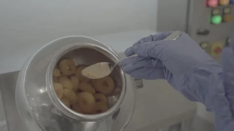 Adding seasoning powder to a rotating drum of cereal rings. 스톡 동영상 330239899