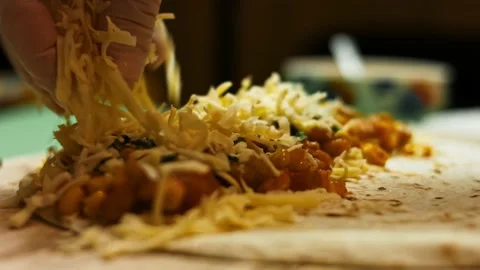 Adding second layer of cheese to flour tortilla filled with vegetables and Stock Footage 151294486